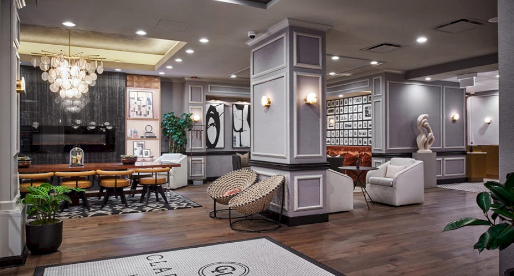The image shows a modern, stylish lounge area with seating, plants, artworks on the walls, and contemporary lighting.
